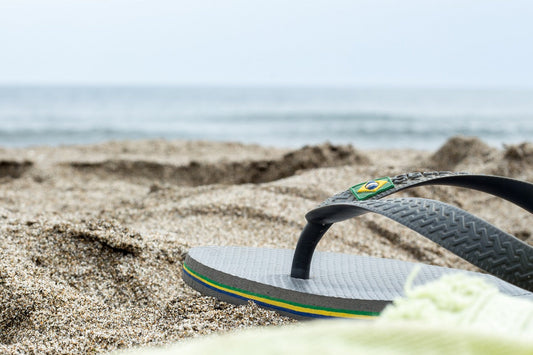 a pair of flip flops on a beach, symbolic of the article which is about recycling flip flops. only the front half is visible not the whole flip flop