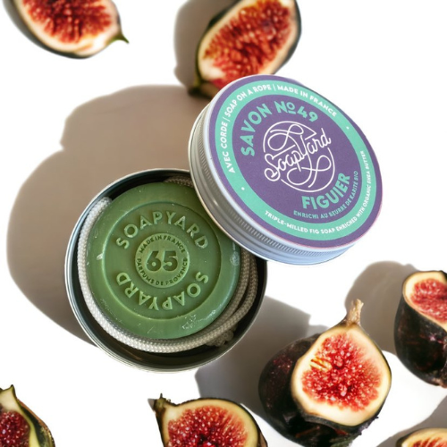 a soap tin with a dark green fig soap on a white backgroudn with ai open figs dotted around