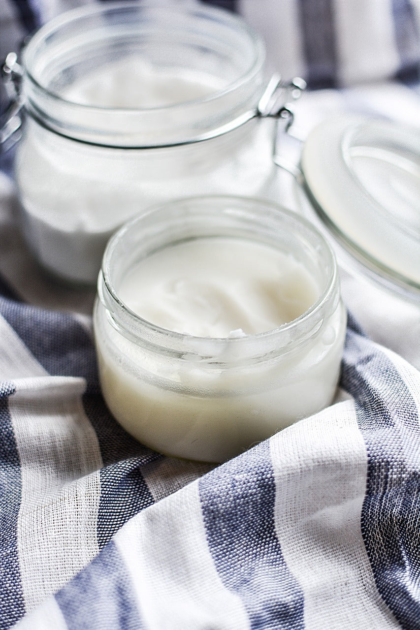 jars of white solidified coconut oil on a blue and white tablecloth