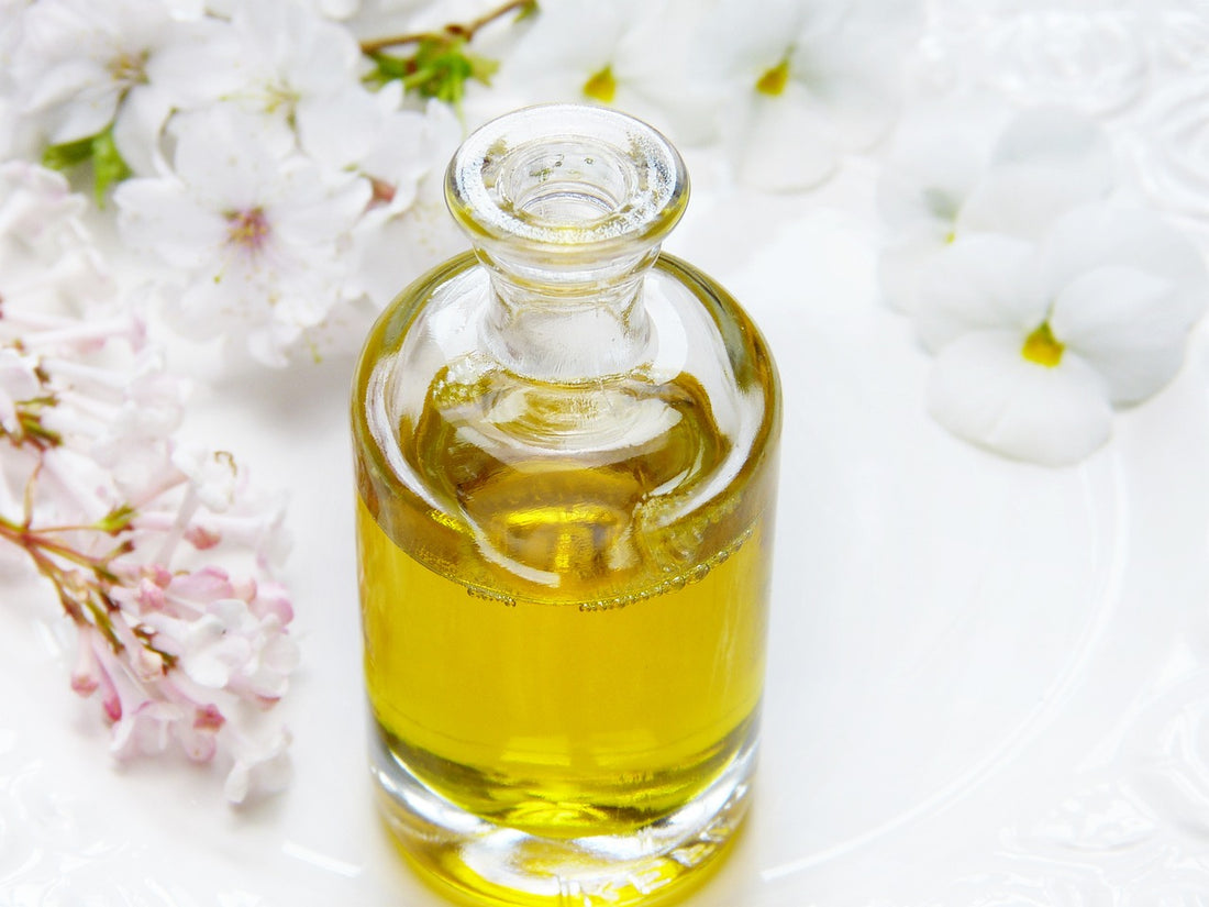 a bottle of oil with white flowers around it 