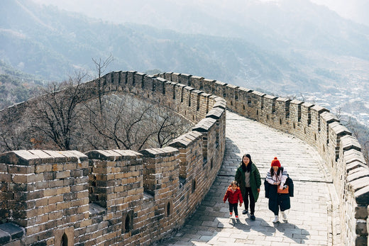 a section of the great wall of china with mountains in the background and some people walking in traditional dress