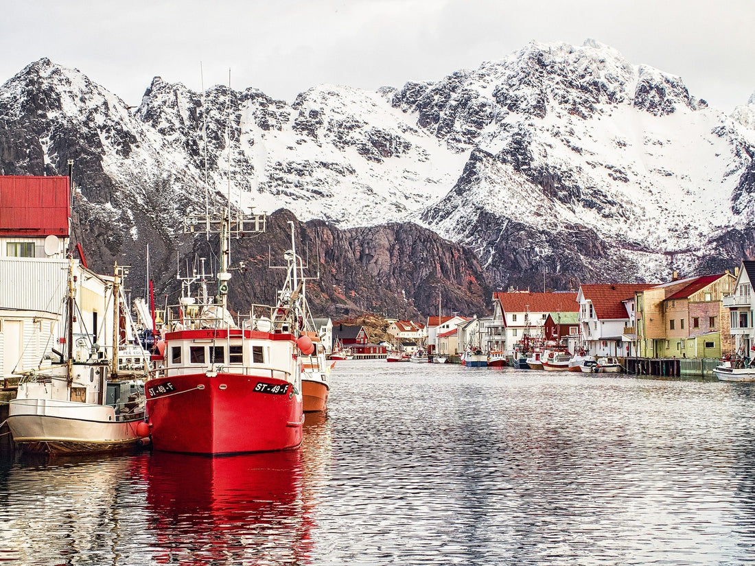 Scenic view of Lofoten Islands, Norway, with colorful fishing huts, towering mountains, and the Northern Lights illuminating the sky.