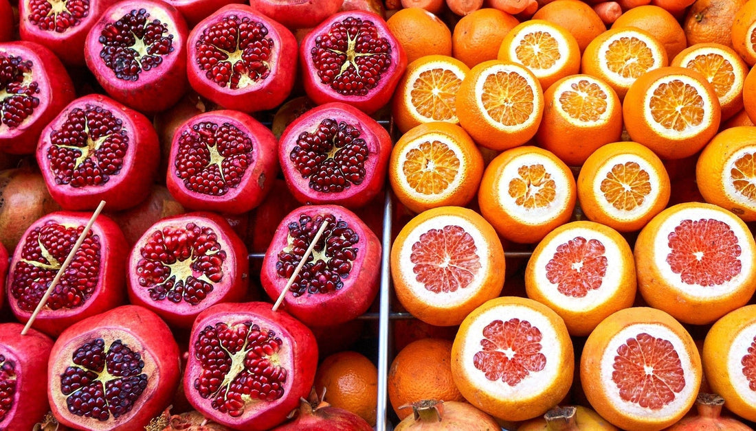 oranges and pomgranates all together with top cut away to reveal pink and orange fruits