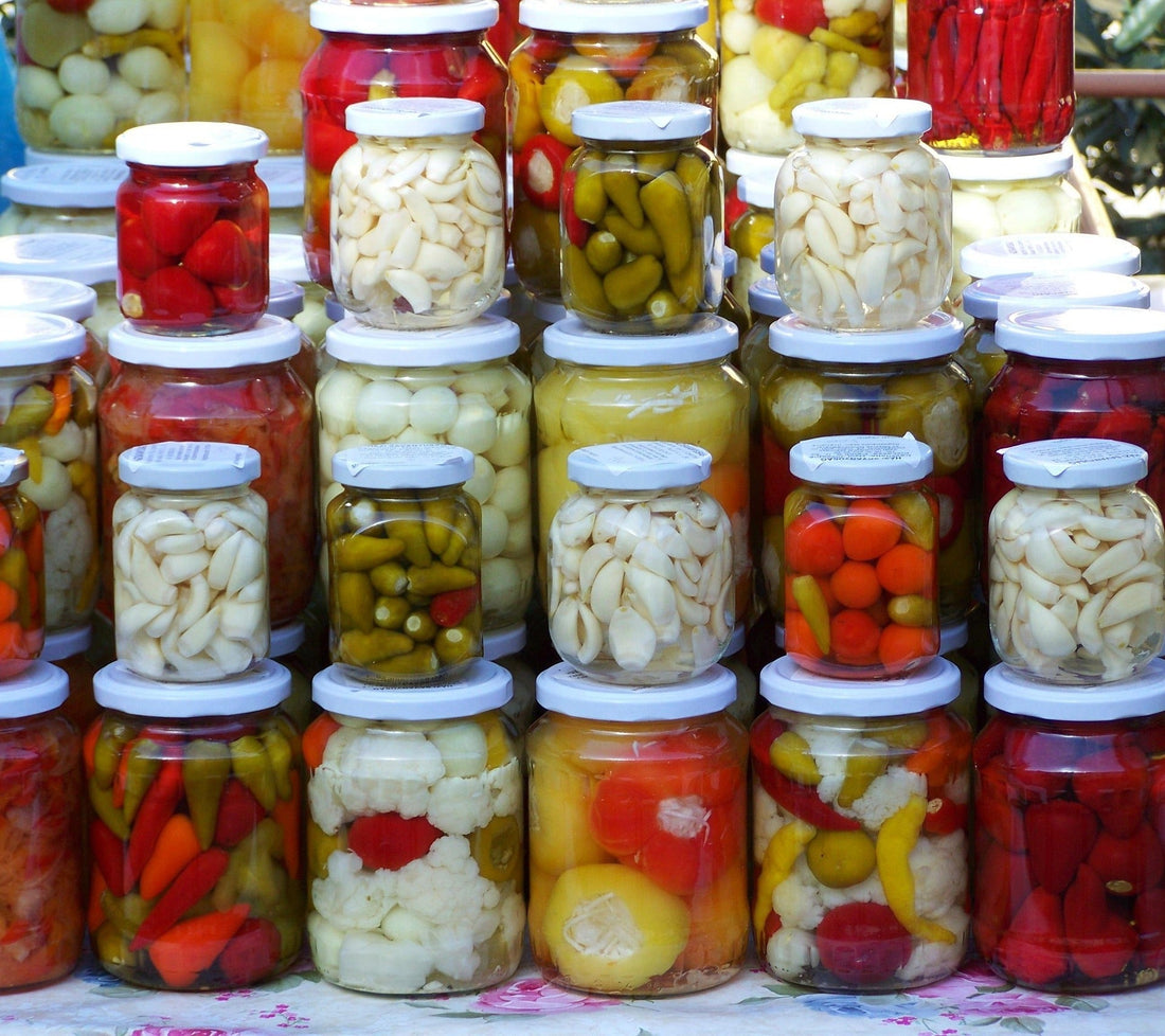 piles of jars of pickles, without labels so look home made pickles, reds greens and white colours big jars stacked with small jars