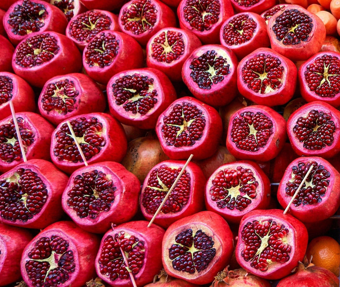 a whole batch of pomegranates opened to reveal the seeds the colours are pinky purple