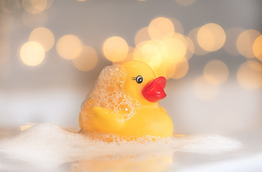 a yello plastic duck with orange beak in soapy water with bubbles