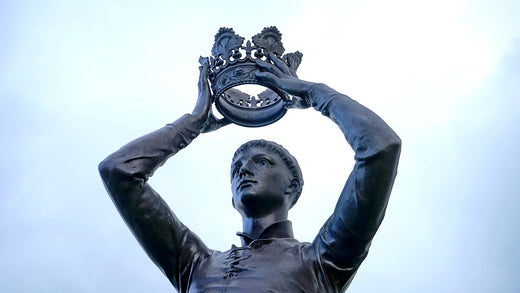 the upper half of a statue of a man raising a crown like macbeth